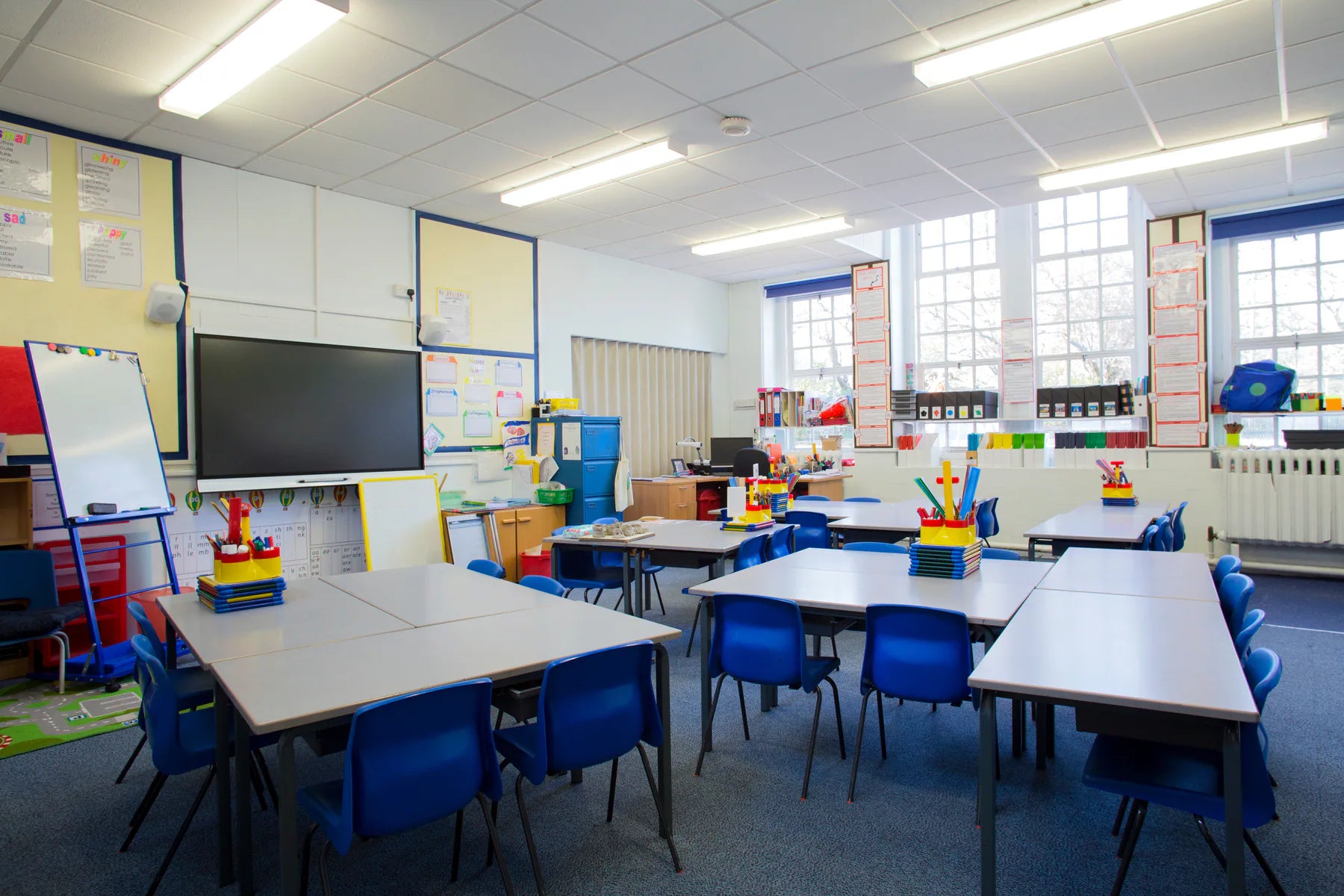 Bright classroom furnished with practical school tables, chairs and teacher storage
